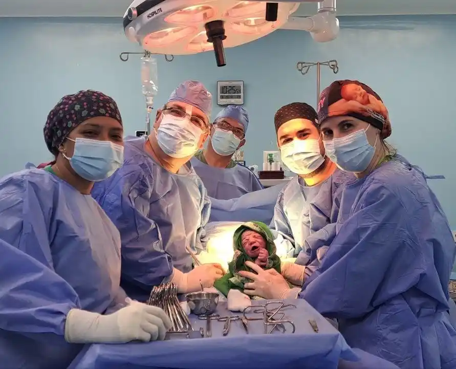 El Dr. Durand y su equipo quirúrgico con un recién nacido tras una cesárea